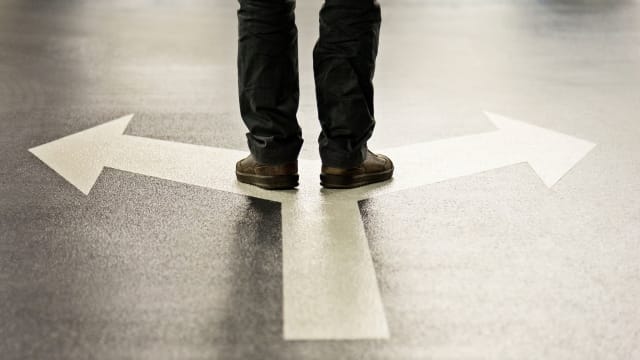 Person standing at the junction of two arrows pointing in opposite directions